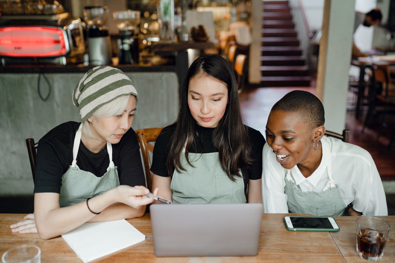Café colleagues reviewing work together on a laptop