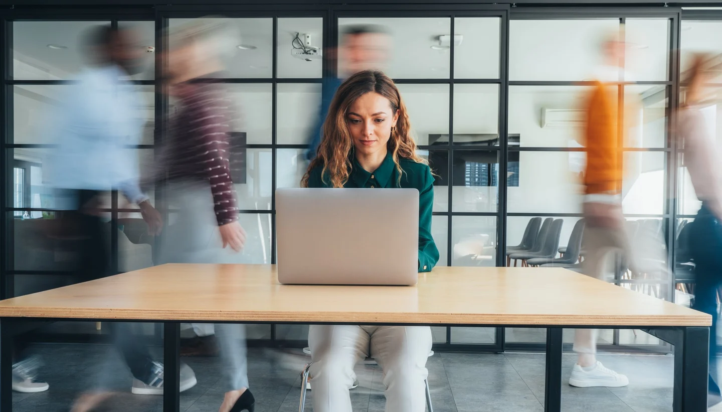 A woman working on a laptop in an office.